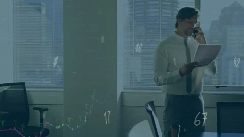 He is reading documents and talking on a mobile phone in an office Stock Footage 327447503