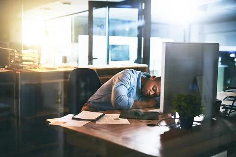 He should have logged off a long time ago. Shot of an exhausted young busines Stock Photos