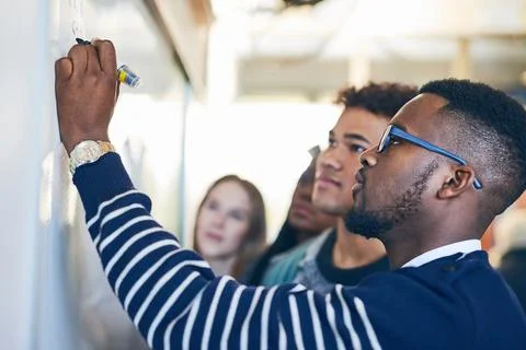 He takes his maths class serious. Shot of a young man writing on a whiteboard Stock Photos