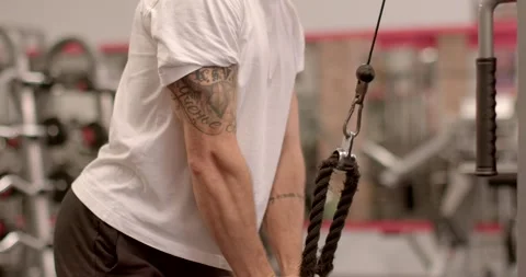 He trains with a cable, lifting and lowering a weight on a rope. Stock Footage 287697786