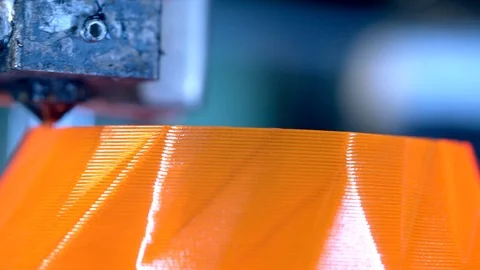 Head of a 3D-printer is creating thin orange layers. 3D printer working at 3d Stock Footage 124203740