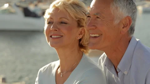 Head and shoulders shot of senior couple sitting together by marina in sunset Stock Footage