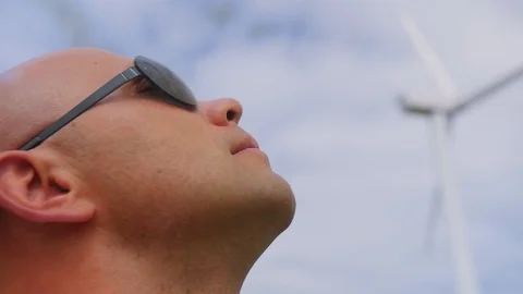 The head of a bald man against the background of the sky and wind turbines Stock Footage 115132818
