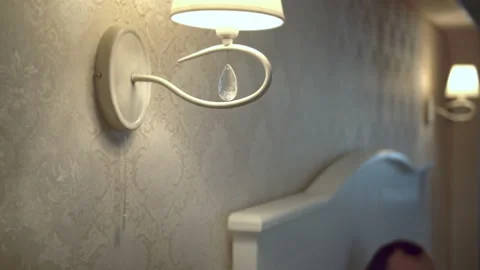 At the head of the bed in the bedroom, a man turns on the night light Stock Footage 154660146