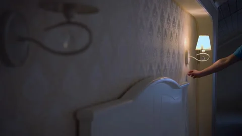 Head of the bed with a burning lamp, the man turns off the light at night Stock Footage 154011841