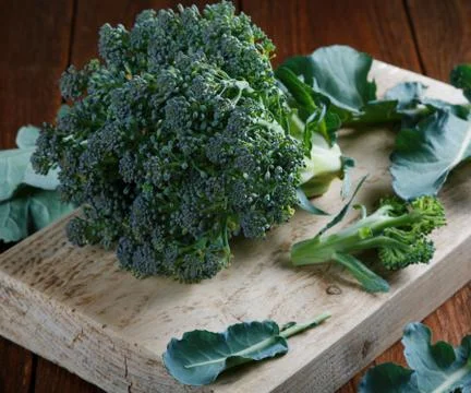 A head of broccoli with leaves in a table Stock Photos