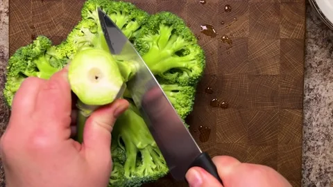 A head of broccoli is separated into florets using a knife 스톡 동영상 321490557