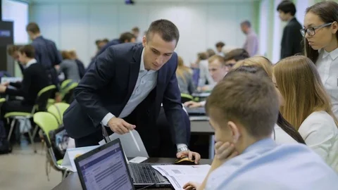 Head of business games help one of the teams. He explains to them using the Stock Footage 70747070