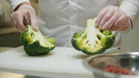 Head chef cutting broccoli with knife on white desk in restaurant cafe kitchen Stock Footage 253578265