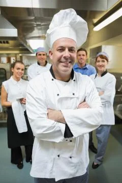 Head chef posing with his team behind him Fotos de archivo