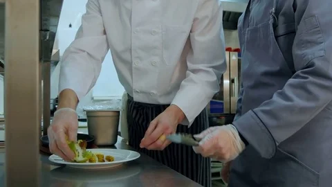 Head chef showing his assistant how to serve the salad Vídeos de archivo 72324793