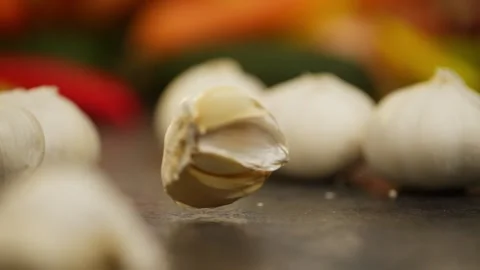 A head of garlic falls on a dark table and scatters into cloves. Stock Footage 296361945