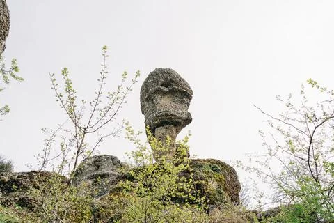 Head shape rock boulder standing on a mountain cliff. A hanging stone on the Stock Photos