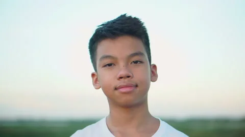 Head shot of Little boy looking at camera with smiling face sunset sky Stock Footage 134589869