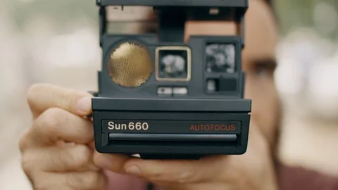 Head on shot of a person using a vintage Polaroid Sun 660 instant film camera. Stock Footage
