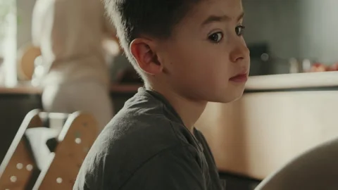 Head shot portrait pensive boy wearinf casual t-shirt sitting in the kitchen Stock Footage 252172157