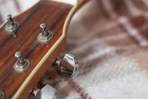 Head of a wood guitar without strings on a plaid Stock Photos