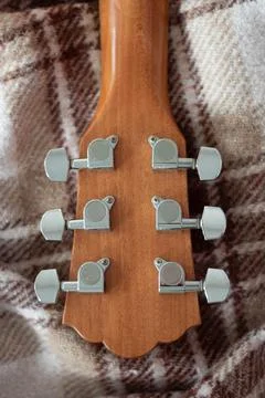 Head of a wood guitar without strings on a brown plaid Stock Photos