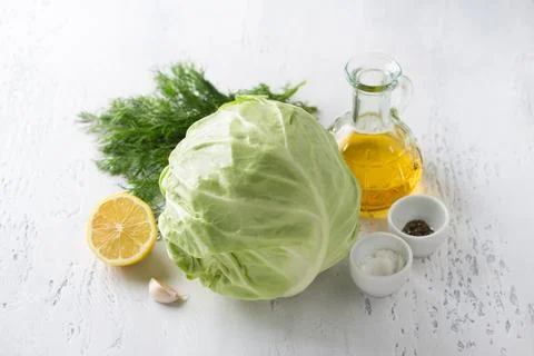 Head of young cabbage, lemon, herbs, vegetable oil, garlic, salt, pepper Stock Photos