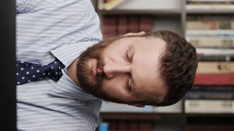 Headache. Vertical orientation of upset bearded man in workplace experiencing Видео 132722981