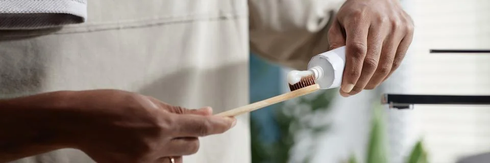 Header Image of Black Man Applying Toothpaste onto Bamboo Toothbrush in Bathroom Stock Photos