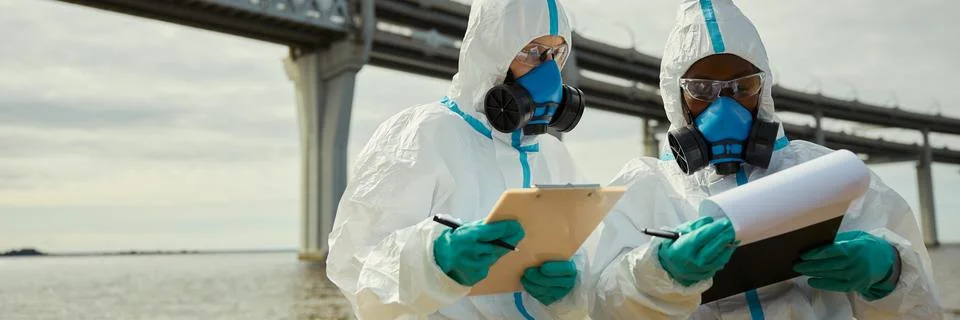 Header of Multiethnic Scientists in Hazmat Suits Inspecting Water Pollution Stock Photos