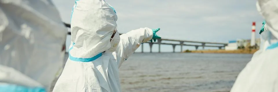 Header of Scientists in Hazmat Suits Inspecting Water Pollution near Plant Stock Photos