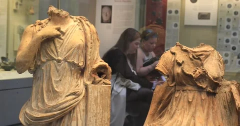 Headless ancient statues with museum visitors in soft focus behind Stock Footage 321020045