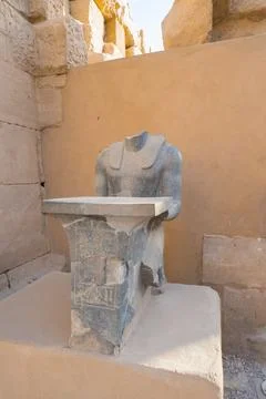 Headless dark stone statue of a pharaoh located at the Karnak temple complex  Stock Photos