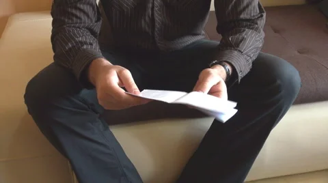Headless shot man opening envelope with bill inside, reading the letter home Stock Footage