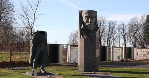 Headless Soviet soldier statue beside stark modernist bust outdoors Stock Footage 321049150