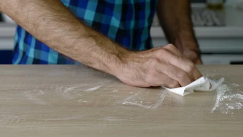 Headless torso of a man cleaning the table of leftover flour Stock Footage 128823879