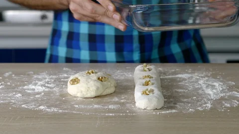 Headless torso of a man putting a small loaf and a loaf of bread with nuts in Stock Footage 128824105