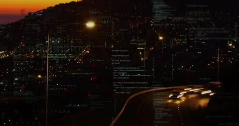 As headlights appearing on hillside highway overlooking city code fragments 動画素材 310151046