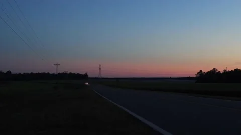 Headlights Single car driving towards camera on a country road at night durin Stock Footage