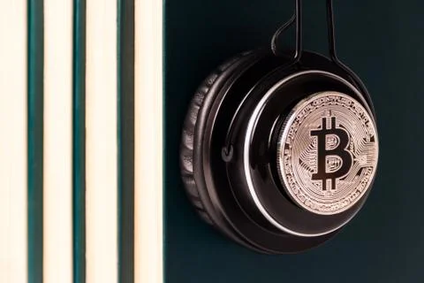 A headphone with a bitcoin symbol on a stack of books close-up. Stock Photos