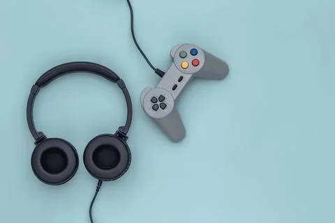 Headphones and game controller on light blue background Stock Photos