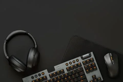 Headphones, computer mouse and keyboard on black background Foto stock
