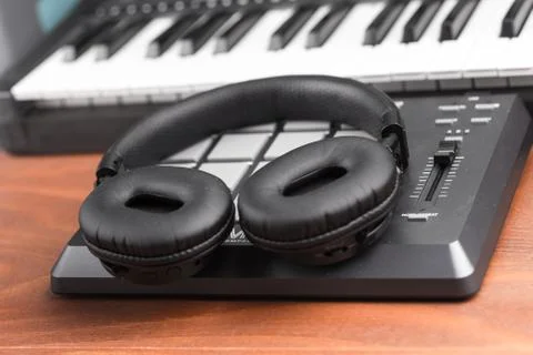Headphones on a drum machine with a keyboard in the background Stock Photos