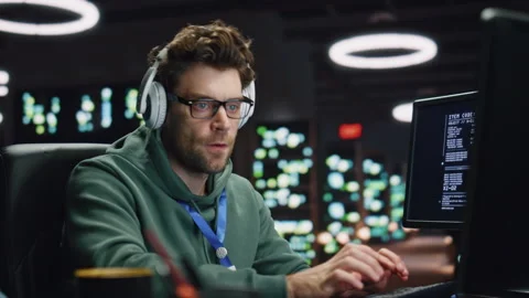 Headphones man coding computer in server room closeup. Developer listening music Stock Footage 260243761