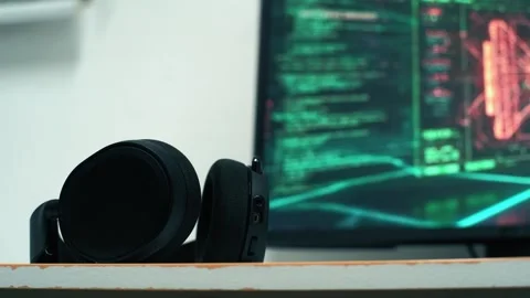 Headphones resting on a shelf with computer code in the background Stock Footage 318443986