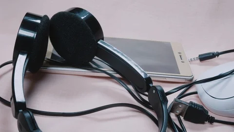 Headphones, smartphone and computer mouse close-up 4K Stock Footage 100707584