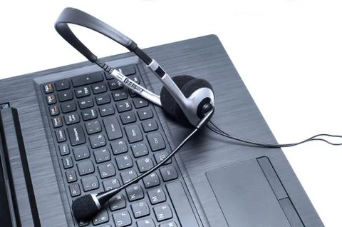 Headset lying on a laptop computer keyboard Stock Photos