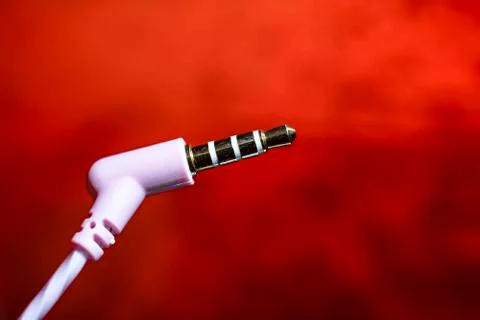Headset plug close-up on a red background macro photo. Stock Photos