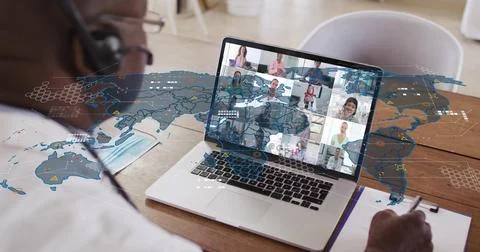 Headset-wearing man writing notes during health meeting, laptop loading data Stock Photos