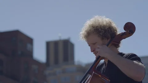 Headshot of cello player playing on rooftop in New York City Stock Footage 111043963