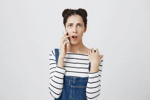 Headshot of clueless young caucasian brunette woman in denim clothes looking Stock Photos