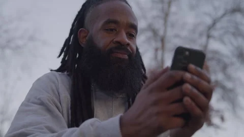 Headshot of Diverse Man with Dreadlocks and Beard Scrolling on Cell Phone at Stock Footage 270400256