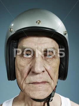 A headshot of a frowning senior man wearing a crash helmet Stock Photos