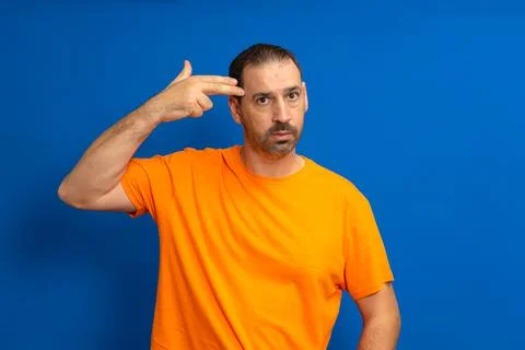 Headshot, kill me please. Depressed man with beard wearing orange T-shirt com Stock Photos